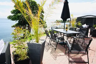 a patio with a table and chairs and the ocean at Chandlers Country House in Rothesay