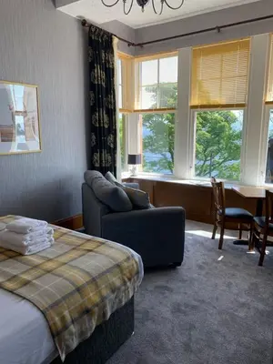 a bedroom with a bed and a couch and a table at Chandlers Country House in Rothesay