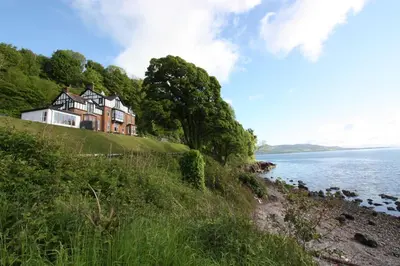 a house on a hill next to a body of water at Chandlers Country House in Rothesay