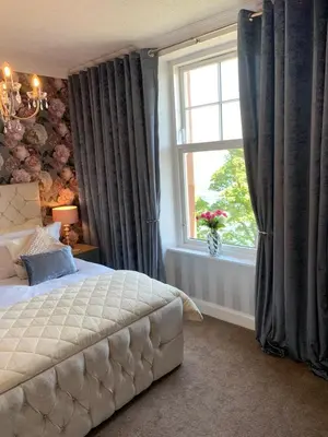 a bedroom with a bed and a window with curtains at Chandlers Country House in Rothesay