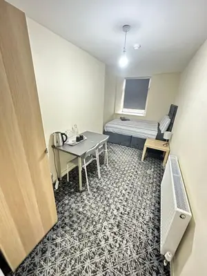 a small room with a table and a bed at Rangers GuestHouse in Glasgow