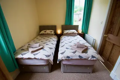 two beds in a small room with green curtains at Tigh Muileann in Killin