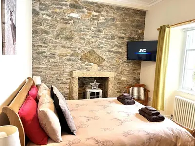 a bedroom with a bed and a stone wall at Tigh Muileann in Killin