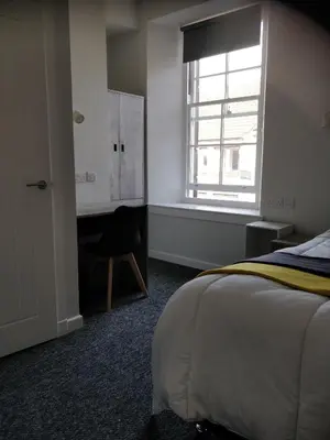 a bedroom with a bed and a desk and a window at The Arches - The Big Yin in Stirling