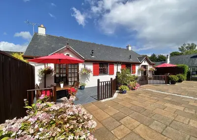 a house with a patio with an umbrella at Heather Cottage Luss in Luss