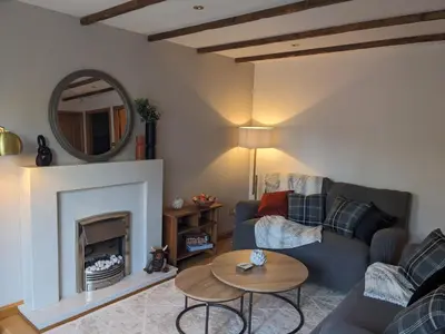 a living room with a couch and a fireplace at Heather Cottage Luss in Luss
