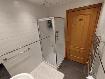 a bathroom with a shower and a toilet and a wooden door at Heather Cottage Luss in Luss