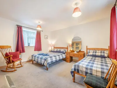 a bedroom with two beds and a desk and a chair at Brondeg Lodge in Crarae
