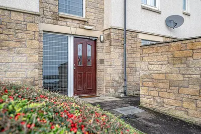 a brick building with a wooden door and flowers at Super Prime Train Station Inverkeithing by TBA in Inverkeithing