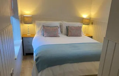 a bedroom with a large white bed with two pillows at Hillview Cottage in Edinburgh