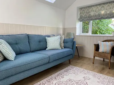 a blue couch in a living room with a window at Hillview Cottage in Edinburgh