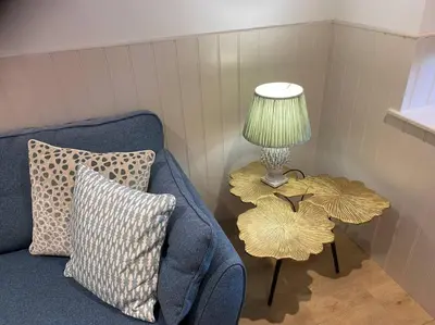 a living room with a blue couch and a table with a lamp at Hillview Cottage in Edinburgh
