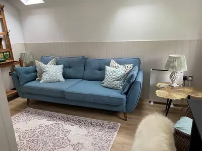 a blue couch in a living room with a rug at Hillview Cottage in Edinburgh