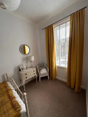 a bedroom with a bed and a dresser and a window at Castle Brae Apartment in Stirling