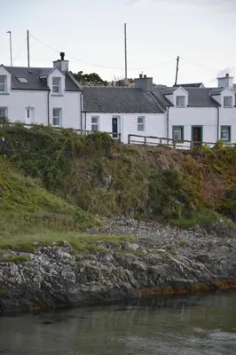 a group of houses on a hill next to a river at Seal Cottage in Portnahaven