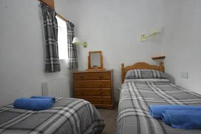 a bedroom with two beds and a dresser and a mirror at Seal Cottage in Portnahaven