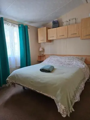 a bedroom with a large bed with blue curtains at Loch Earn Holiday Home in Saint Fillans