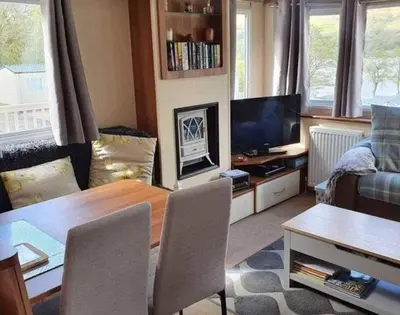 a living room with a dining table and a television at Loch Earn Holiday Home in Saint Fillans