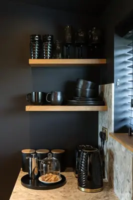 a counter with plates and bowls on a shelf at The Black Cabin Oban in Oban