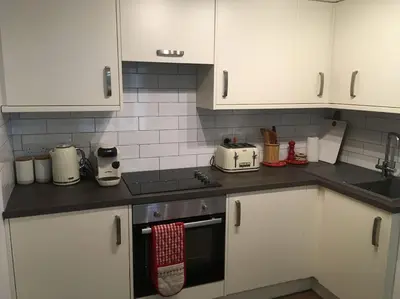 a kitchen with white cabinets and a stove top oven at Caledonian - Charming Central 1 Bed Flat in Edinburgh