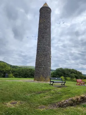 a park bench sitting in front of a stone lighthouse at Apartment - Largs - Sleeps 4 - Pet Friendly in Largs