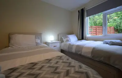 two beds in a room with a window at Ardview Cottage in Oban