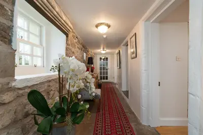 a hallway with a vase of flowers on a red rug at Castle Gogar Cottage in Edinburgh