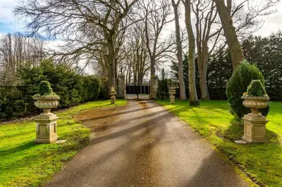 a road in a park with two large vases at Castle Gogar Cottage in Edinburgh