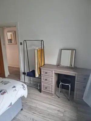 a bedroom with a dresser with a mirror and a bed at Lido Bay Ground Floor Apartment in Largs