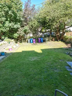 a yard with a large lawn with a group of trash cans at Lido Bay Ground Floor Apartment in Largs