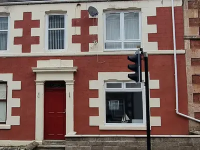 a red and white building with a red door and a traffic light at Lido Bay Ground Floor Apartment in Largs