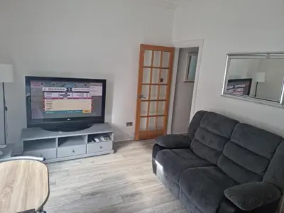 a living room with a couch and a flat screen tv at Lido Bay Ground Floor Apartment in Largs