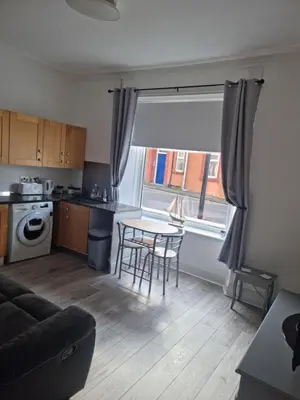 a living room with a table and a kitchen at Lido Bay Ground Floor Apartment in Largs