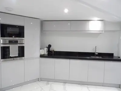 a white kitchen with white cabinets and a sink at Modern 3BHK near Edinburgh zoo in Edinburgh