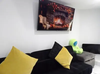 a living room with a black couch and a fireplace at Modern 3BHK near Edinburgh zoo in Edinburgh