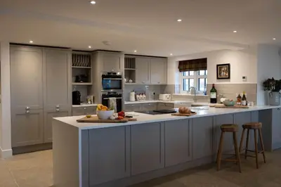 a kitchen with white cabinets and a large island with bar stools at Kipney Hunting Lodge in Perth