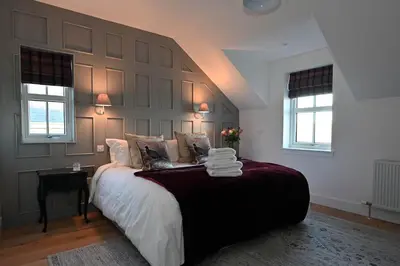 a bedroom with a large bed and two windows at Kipney Hunting Lodge in Perth