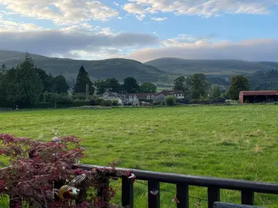 a field of green grass with mountains in the background at Honeycomb Lodge in Dollar