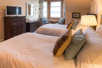 a hotel room with two beds and a television at The Cedars Guest House in Dunoon