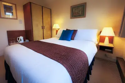 a hotel room with a large white bed with blue pillows at The Cedars Guest House in Dunoon