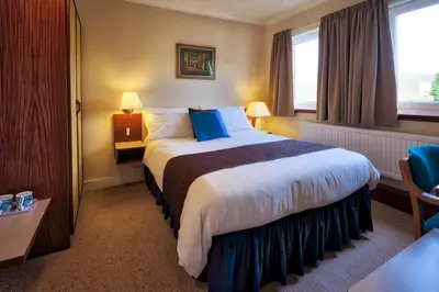 a hotel room with a large bed with blue pillows at The Cedars Guest House in Dunoon