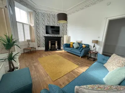 a living room with a blue couch and a fireplace at Stunning West End Flat! in Glasgow