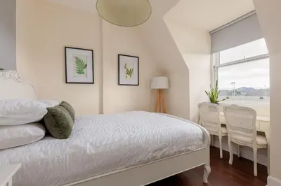 a bedroom with a bed and a table and chairs at Stylish Victorian Apartment's close to the Botanical gardens, Free parking! in Edinburgh