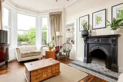 a living room with a fireplace and a couch at Stylish Victorian Apartment's close to the Botanical gardens, Free parking! in Edinburgh