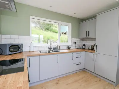 a kitchen with white cabinets and a window at Beech Cottage in Aberfeldy