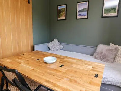 a room with a wooden table and a bed at Beech Cottage in Aberfeldy