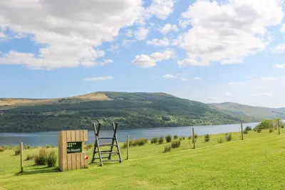 a sign in a field next to a body of water at Beech Cottage in Aberfeldy