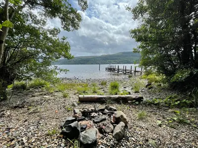 a fire pit on the shore of a lake at Beech Cottage in Aberfeldy