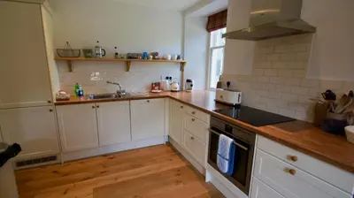 a kitchen with white cabinets and a stove top oven at Edinample Lodge in Lochearnhead