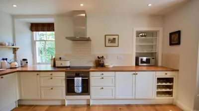 a kitchen with white cabinets and a counter top at Edinample Lodge in Lochearnhead